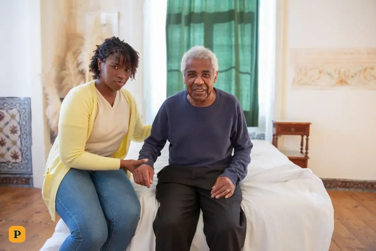 A daughter sits with her older father and holds his hand