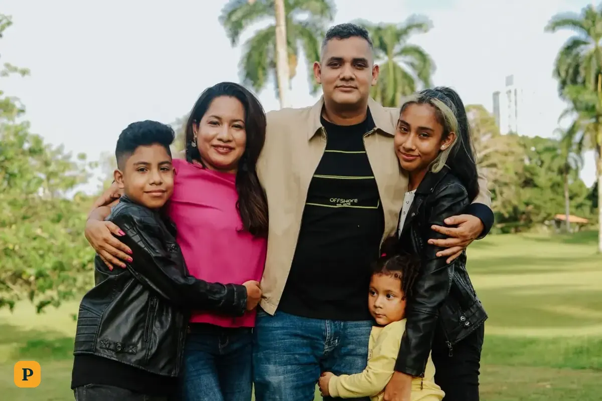 Una familia sonriente de cinco personas posa junta en un parque