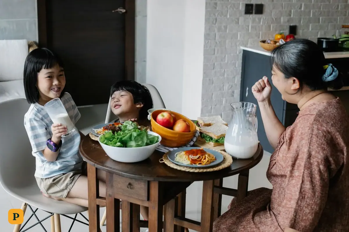 Kasalo ng isang lola ang kanyang mga apo sa almusal sa mesa ng kusina